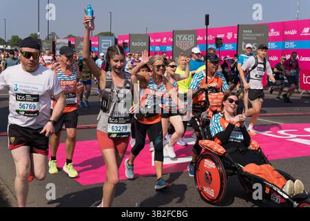Londra, Regno Unito. 27 aprile 2025. Un'atleta disabile siede su una sedia a rotelle mentre familiari e amici la spingono oltre la linea di partenza durante la maratona TCS di Londra per competere su un percorso di 26 km attraverso le strade di Londra. Xiu Bao/Alamy Live News. Foto Stock