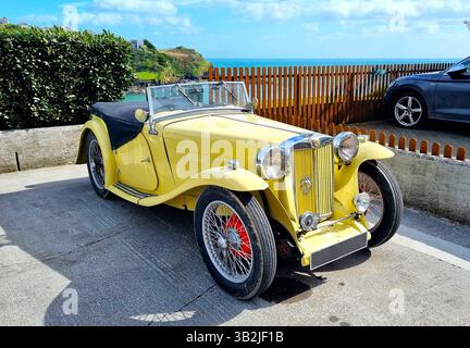 Lussuosa auto sportiva in vinage gialla da collezione in un parcheggio con il mare sullo sfondo Foto Stock