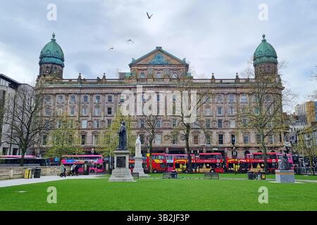Vista del grandioso edificio storico vittoriano commerciale e degli autobus turistici rossi a Belfast, Irlanda del Nord Foto Stock