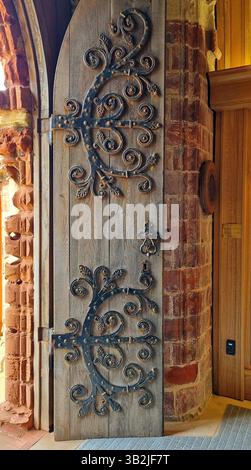 Cerniere ornate con motivi a foglia che decorano e sostengono la porta medievale in legno della navata occidentale della cattedrale di San Magnus a Kirkwall, nelle Orcadi Foto Stock
