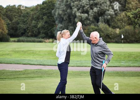 Senior man, golf e istruttore con festeggiamenti, High Five e outdoor su un campo e prato. Fitness, allenatore e campo con vittoria sportiva, salute e. Foto Stock