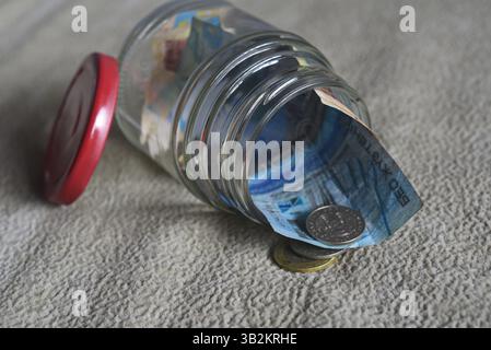 Banconote e monete in un vaso di vetro. Foto Stock