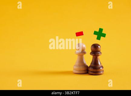 Pensiero o processo decisionale negativo o positivo. Ottimismo o pessimismo. Vantaggi e svantaggi. Pedine scacchistiche con simboli più e meno Foto Stock