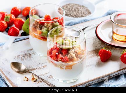 Yogurt al bicchiere con frutti di bosco freschi, muesli e noci per colazione Foto Stock