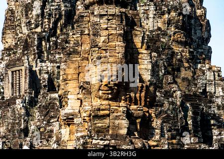Primo piano di una scultura in pietra su un antico tempio, che mostra intricati intagli e texture intemperie, circondati da formazioni rocciose. Foto Stock