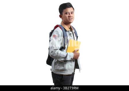 uomo asiatico che indossa una giacca di denim che trasporta una borsa e libri isolati su sfondo bianco Foto Stock