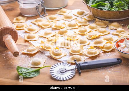 Ravioli crudi, pasta italiana, ripieni di spinaci e formaggio feta, preparati per la cottura Foto Stock