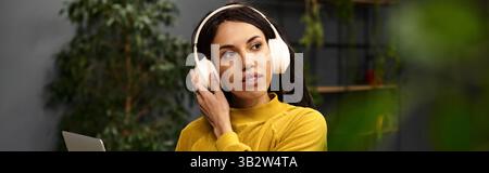 Bella donna professionale che lavora diligentemente in un ufficio moderno e indossa le cuffie. Foto Stock