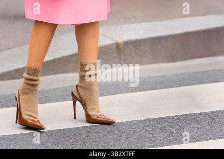 Parigi, Francia - 11 marzo 2025: Parigi, Francia - 11 marzo 2025: Tacchi Brown Saint Laurent indossati con calze beige sul crosswalk. Outfit Street style Foto Stock