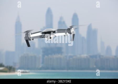 Drone con fotocamera in volo vicino alla città. Veicolo aereo senza equipaggio per la sorveglianza Foto Stock