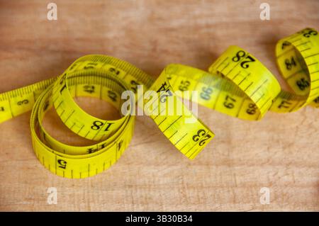 Vista dall'alto del metro a nastro giallo su un tavolo in legno. Concetto di dieta. Foto Stock
