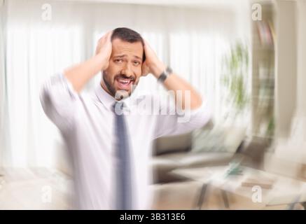 Uomo che perde la mente tenendo la testa e sentendo vertigini Foto Stock