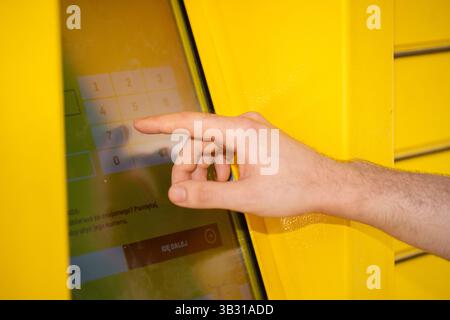 L'utente interagisce con un chiosco touch screen situato in un ambiente giallo brillante Foto Stock