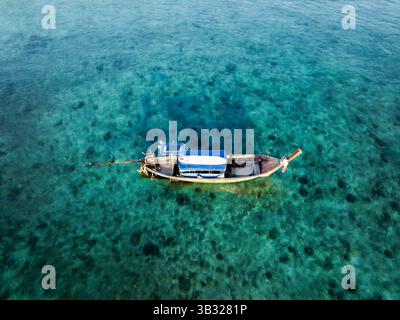 Lancio di un drone di una tradizionale barca a coda lunga tailandese che galleggia sulle limpide acque turchesi della Thailandia. Foto Stock