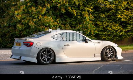 Whittlebury, Northants.,.UK - 27 aprile 2025: Auto Toyota gt86 bianca 2017 che guida su una strada di campagna inglese. Foto Stock