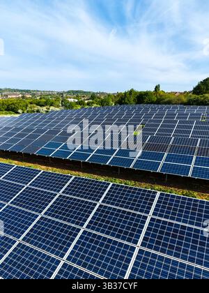 File di pannelli solari fotovoltaici su terreni agricoli che generano energia pulita e sostenibile per uso aziendale e domestico Foto Stock