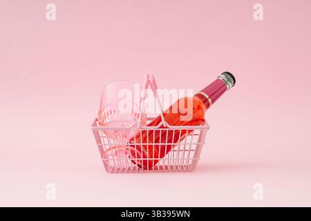 Bevanda all'anguria e bicchiere rosa da bere nel cestino della spesa rosa su sfondo rosa pastello. Concetto di drink estivo rinfrescante e minimalista. Foto Stock