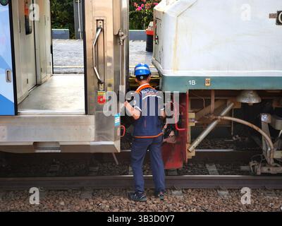 Un ufficiale autorizzato sta controllando il collegamento della locomotiva con il vagone ferroviario Foto Stock