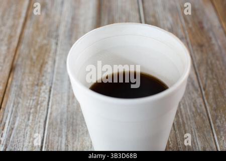 Vista ravvicinata di un caffè nero all'interno di una tazza bianca in polistirolo. Foto Stock