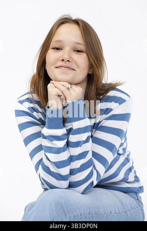 Una giovane donna allegra e vivace posa felicemente in un elegante maglione a righe, che irradia un sorriso coinvolgente Foto Stock