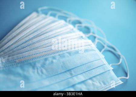 Maschere chirurgiche protettive blu su sfondo blu. L'isteria del coronavirus (COVID-19) sta causando carenze di maschere di massa all'inizio del 2020 Foto Stock