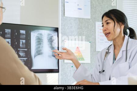 Medico che esamina la radiografia polmonare e diagnostica del paziente per malattie respiratorie al momento della consultazione ospedaliera Foto Stock