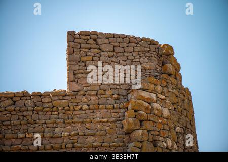 Una vista ravvicinata di un antico muro di pietra romano, che mostra le texture intemperie, le intricate murature e l'artigianato senza tempo dell'architettura romana Foto Stock