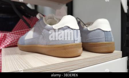 Eleganti sneaker blu e bianche con suola in gomma sullo scaffale Foto Stock