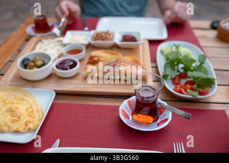 Colazione tradizionale turca con pane fresco, olive, formaggio, pomodori, cetrioli, e varietà di inceppamenti e spalmazioni. Godibile in un ambiente vivace Foto Stock