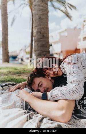 Una giovane coppia che abbraccia felicemente all'aperto sotto le palme in una giornata di sole Foto Stock