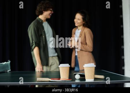 Due colleghi possono godersi un momento di luce mentre condividono caffè e conversazione in un ambiente di lavoro vivace. Foto Stock