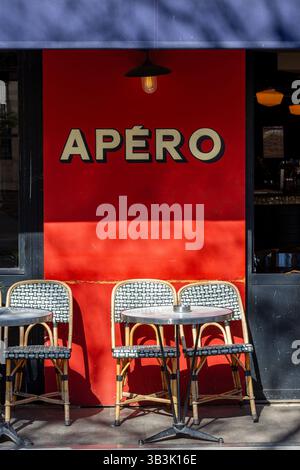 Terrazza caffetteria parigina con tavolino e due sedie sotto il testo Apéro, che significa aperitivo in francese Foto Stock