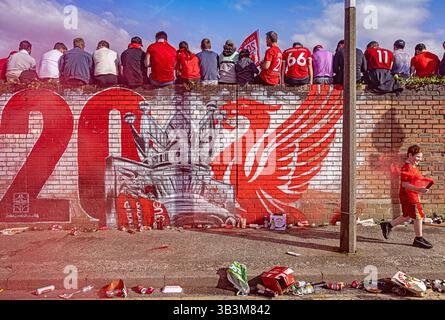 I tifosi del Liverpool celebrano la vittoria del loro club fuori dal pub Sandon, seduti su un vivace murale LFC ad Anfield. Foto Stock