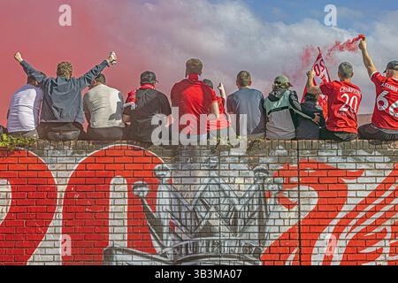 I tifosi del Liverpool celebrano la vittoria del loro club fuori dal pub Sandon, seduti su un vivace murale LFC ad Anfield. Foto Stock