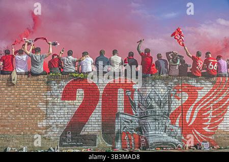 I tifosi del Liverpool celebrano la vittoria del loro club fuori dal pub Sandon, seduti su un vivace murale LFC ad Anfield. Foto Stock