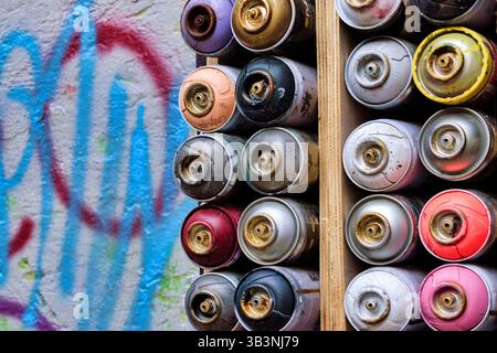 Decorazioni a parete con vecchie bombolette di vernice spray usate. Sfondo con bombolette spray multicolore Foto Stock