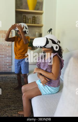 Giocare ai fratelli afroamericani usando occhiali VR sul divano nel salotto di casa, copiare spazio Foto Stock