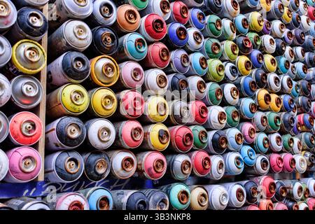Decorazioni a parete con vecchie bombolette di vernice spray usate. Sfondo con bombolette spray multicolore Foto Stock
