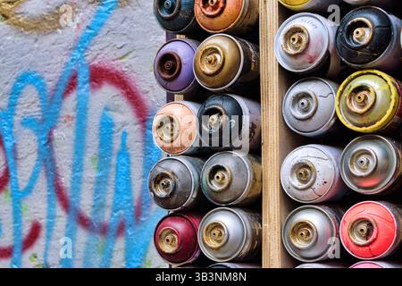 Decorazioni a parete con vecchie bombolette di vernice spray usate. Sfondo con bombolette spray multicolore Foto Stock