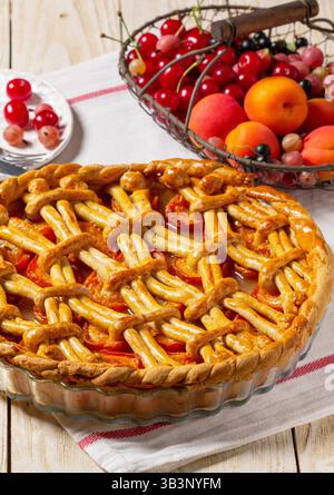 Torta di albicocche decorata con decorazioni a base di impasto e un cestino di metallo con frutta e frutti di bosco. Foto Stock
