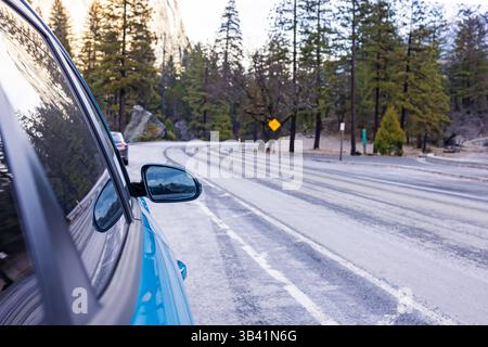 Guida panoramica lungo una strada tortuosa in un'area boschiva vicino al Parco Nazionale di Yosemite durante l'inverno Foto Stock