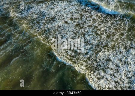 Ripresa aerea che cattura il contrasto tra le onde oceaniche scure e la schiuma di mare bianca brillante, il principe edward Island Canada. Foto di alta qualità Foto Stock