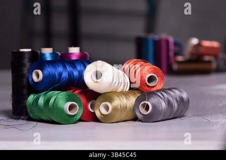 Gruppo di bobine metalliche filettature colorate che si trovano sul tavolo. Utensili da cucire per stilisti professionisti o per cucire hobby. Foto Stock