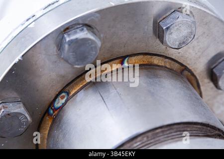 Una sezione di un tubo saldato con una flangia in acciaio inox con bulloni avvitati. Foto Stock
