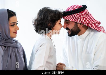 Famiglia araba felice che indossa abiti in arabia saudita trascorre del tempo insieme a casa - genitori e bambini sauditi del Medio Oriente giocano, concetti sulla parità Foto Stock