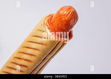 Hot dog grigliato in panino tostato con ketchup, isolato su sfondo bianco, concetto di primo piano di fast food. Foto Stock