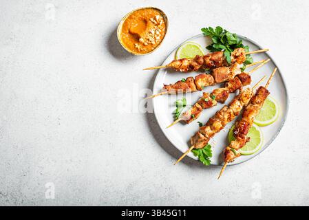 Spiedini di satay di pollo malese con salsa di arachidi su sfondo bianco, vista dall'alto, spazio per copiare. Sate Ayam, cucina asiatica tailandese. Foto Stock