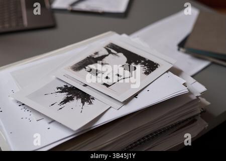 Pila di carte con rorschach, test in piedi sulla scrivania di psicologo scolastico con laptop e blocco note con penna Foto Stock