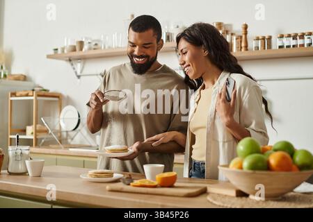 Una coppia gioiosa condivide un momento speciale cucinando una deliziosa colazione insieme. Foto Stock