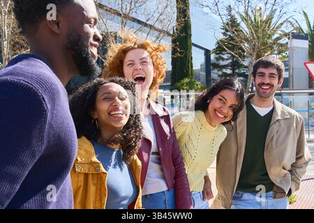 Gruppo di allegri giovani amici multirazziali che si divertono insieme nella vivace città, celebrando l'unità e l'amicizia Foto Stock